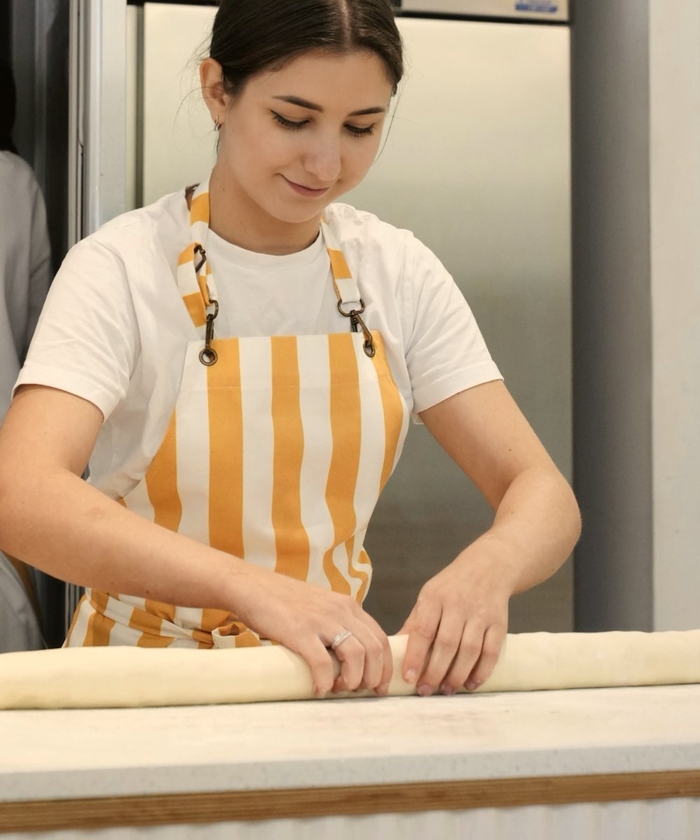 A baker rolling out dough in the bakery kitchen